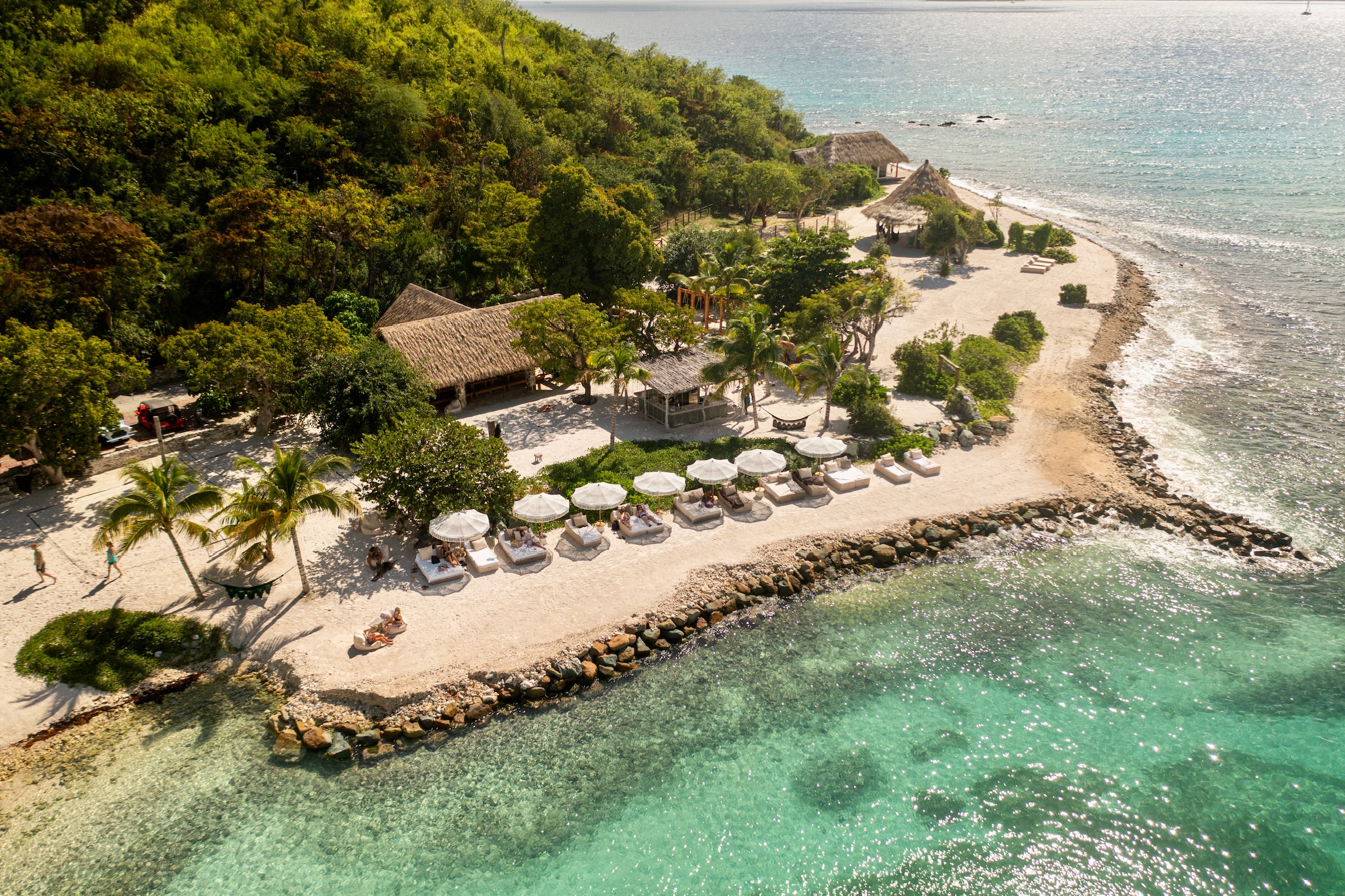 Beachfront daybeds and umbrellas along the shore of The Aerial, BVI