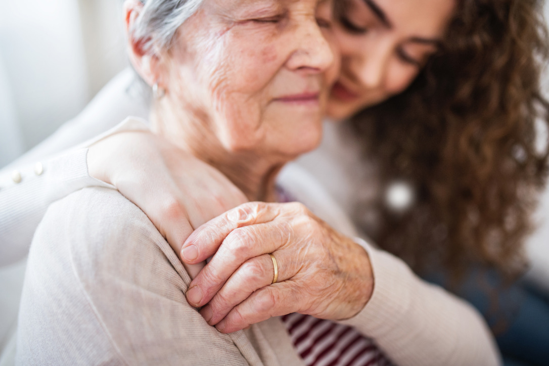 A senior woman embraced by a caregiver